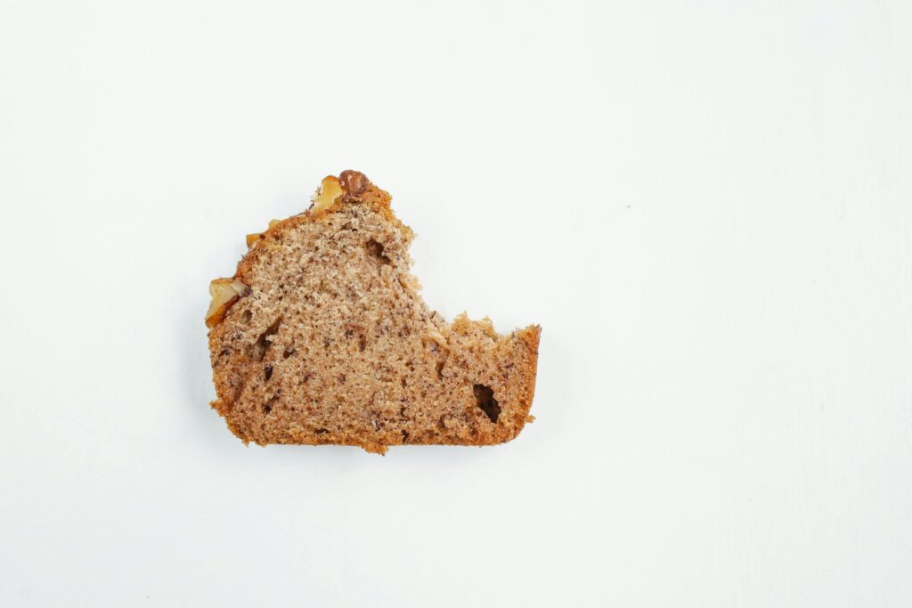 A mouthwatering slice of banana bread on a white surface, showcasing texture.